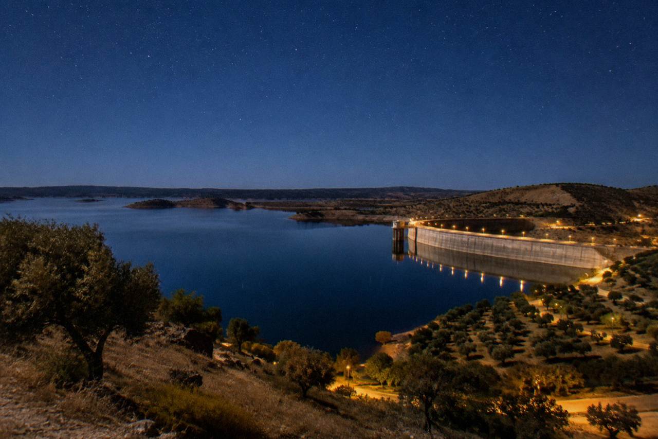 A wide night sky full of stars above the still water of the Alqueva lake in the Alentejo