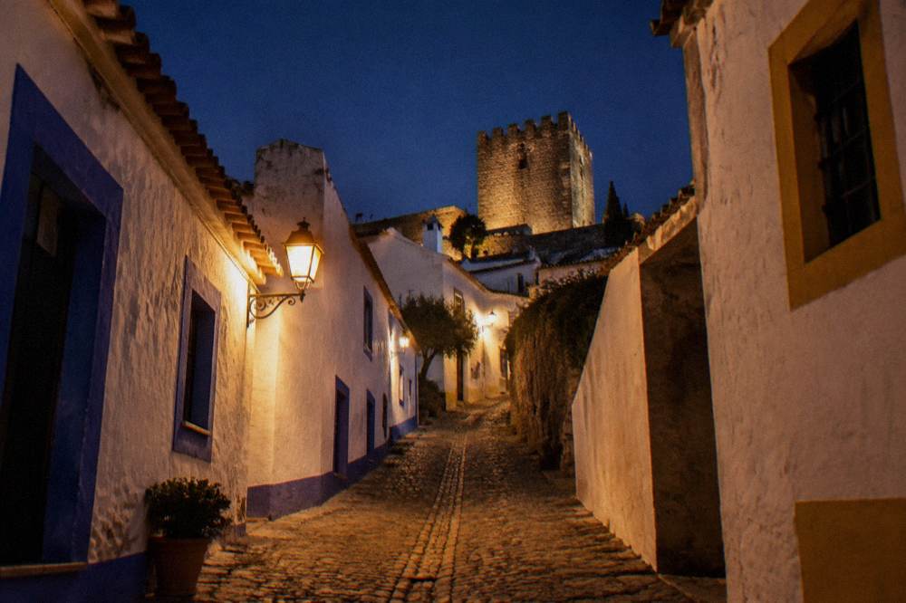 Narrow whitewashed street in Monsaraz village lit by a single lamp at night