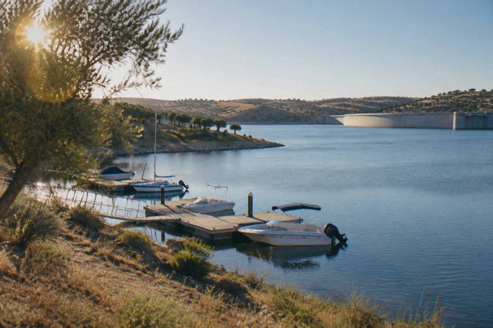 Boats moored on a wooden jetty at a quiet inlet of the Alqueva reservoir