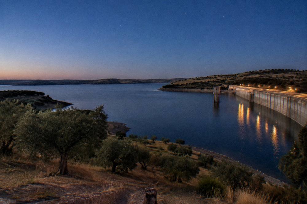 Evening sky over the Alqueva reservoir with the first stars appearing above dark water