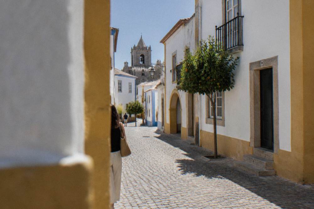Stone fortress walls and bell towers of a border town under a clear afternoon sky