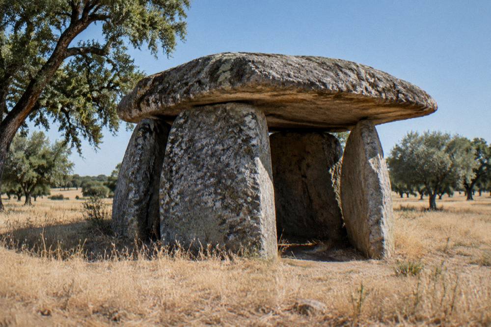 A large single-chamber stone dolmen standing alone in dry golden grassland