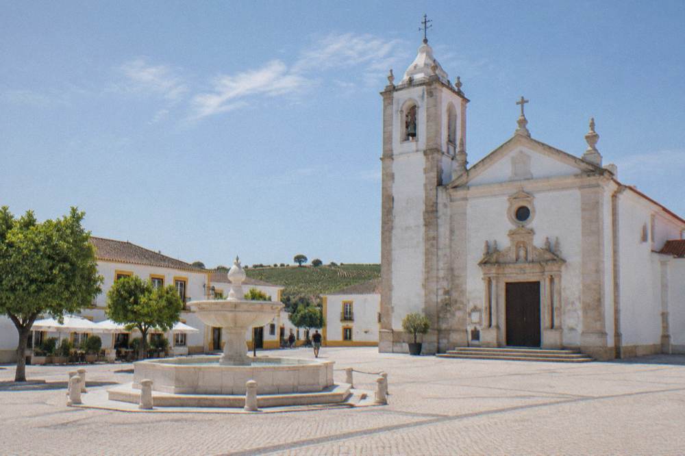 A pale marble church facade with carved details in an Alentejo town