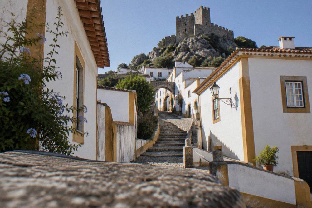 Stone castle keep standing above red-tiled rooftops of a hill town