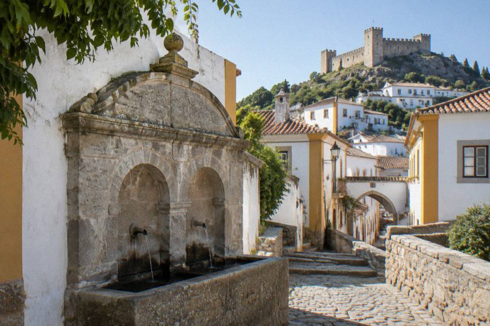 Carved stone fountain with arched niches at the entrance to an old Portuguese town