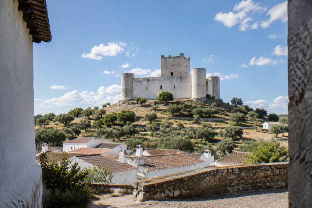 Pentagonal stone keep of Évoramonte castle seen from below against scattered clouds