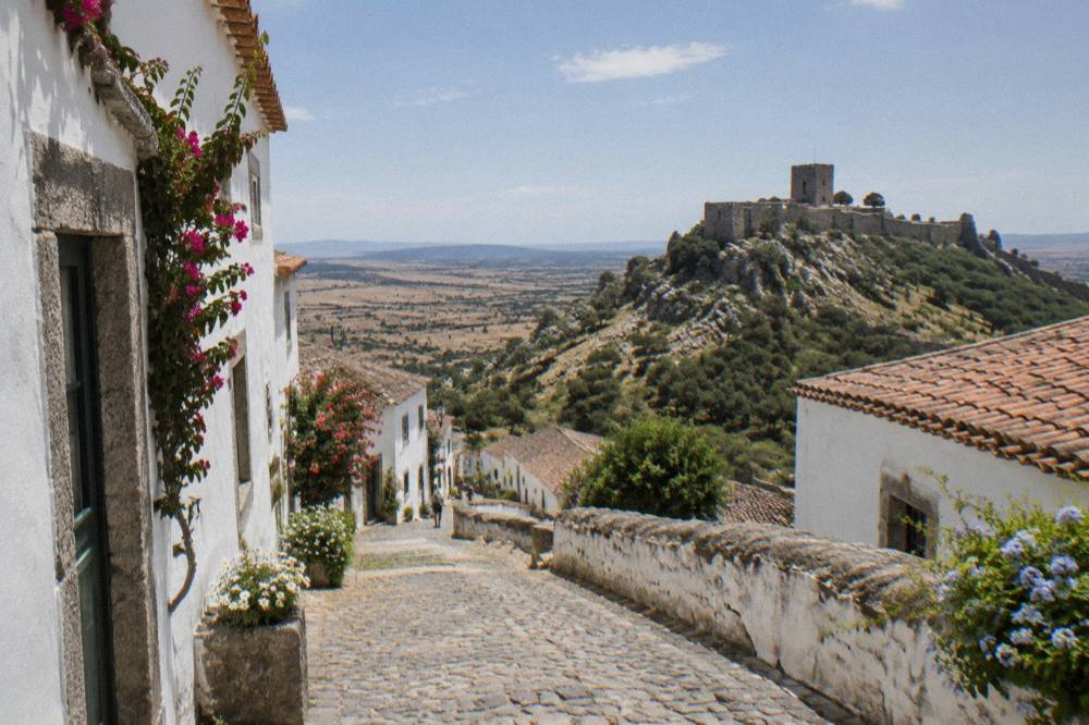 Steep cobbled lane in a whitewashed hill village with granite trim and flowers on the walls