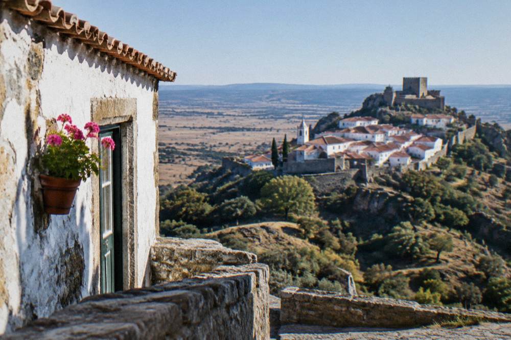 A small Alentejo hill town with white houses and a church tower seen across a valley