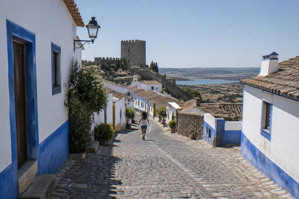 Cobblestone main street of Monsaraz with whitewashed houses and blue trim