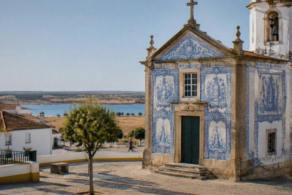 A church façade with blue and white azulejo tiles in a small Alentejo square