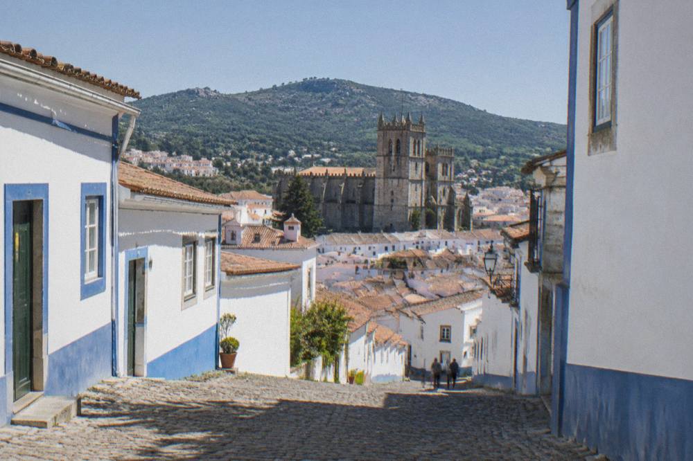 A steep cobbled lane in Portalegre with white houses and blue trim under a clear sky