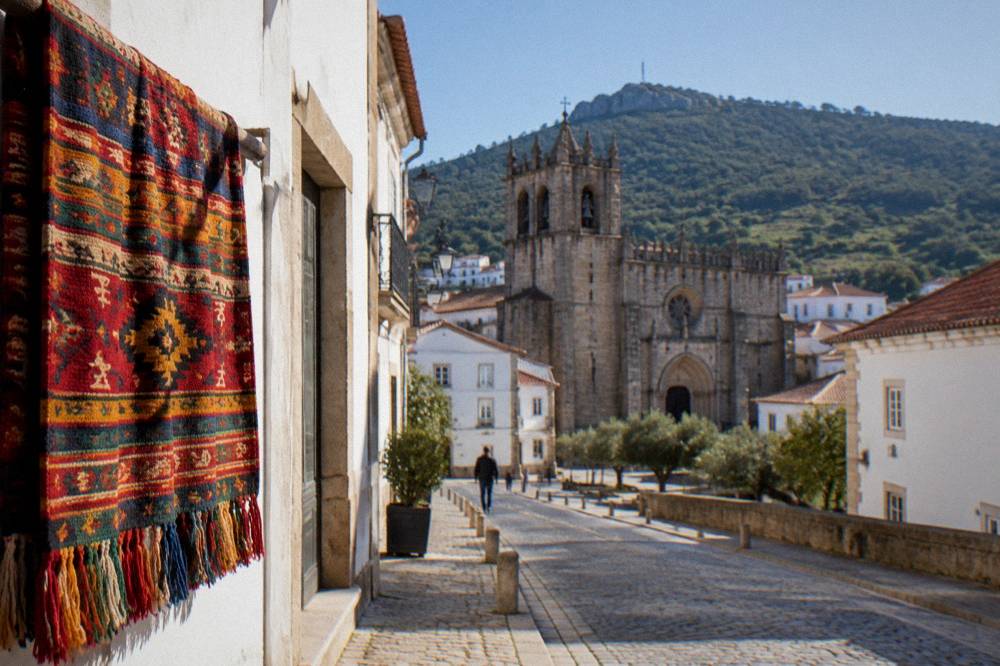 A detailed woven wall hanging in rich colours draped over a wooden bar