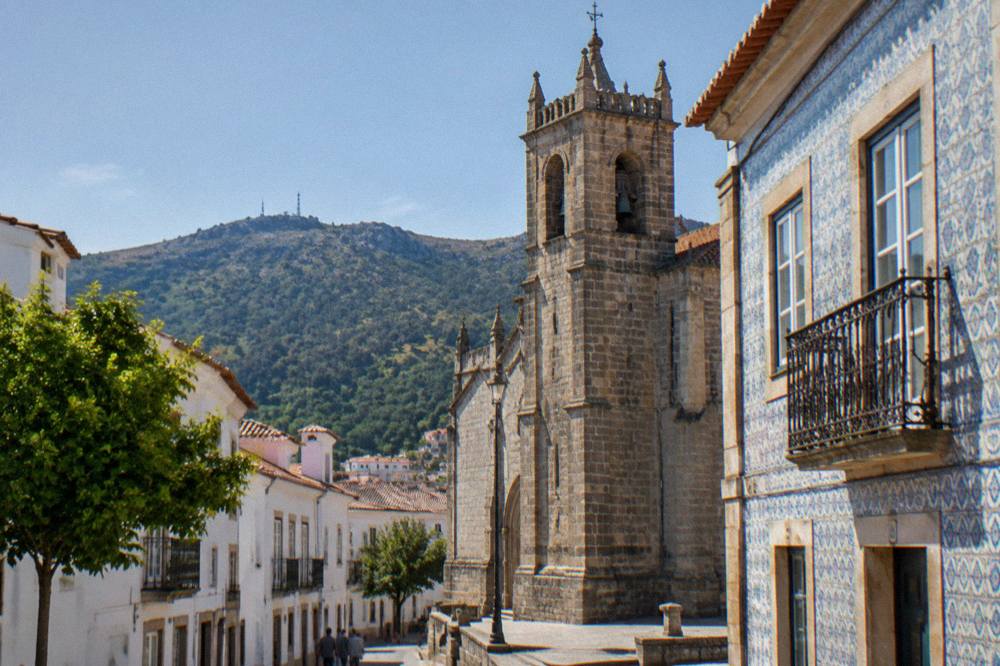 A church tower and tiled facade on a Portalegre street in late afternoon light