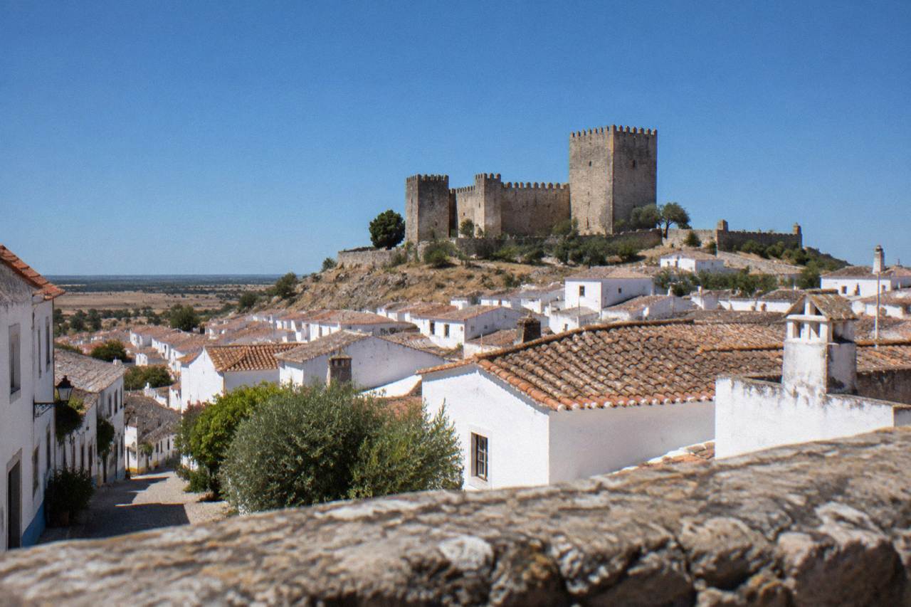 A small Alentejo town of white houses clustered beneath a hilltop castle under a wide blue sky