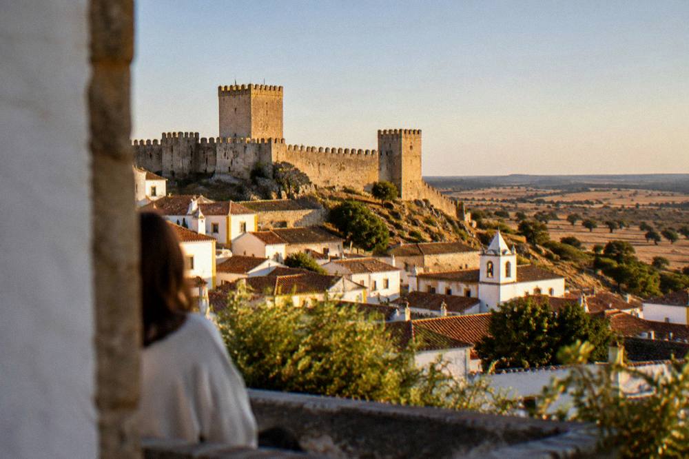 Golden evening light over white village rooftops and rolling farmland in southern Portugal