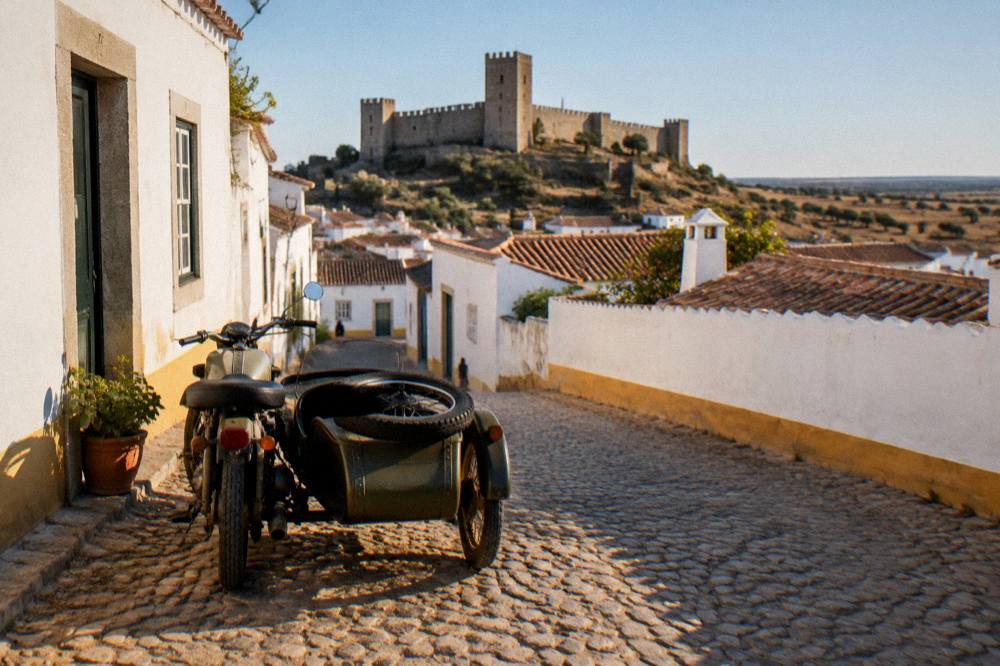 A vintage motorcycle sidecar parked on a cobbled street beside white Alentejo buildings