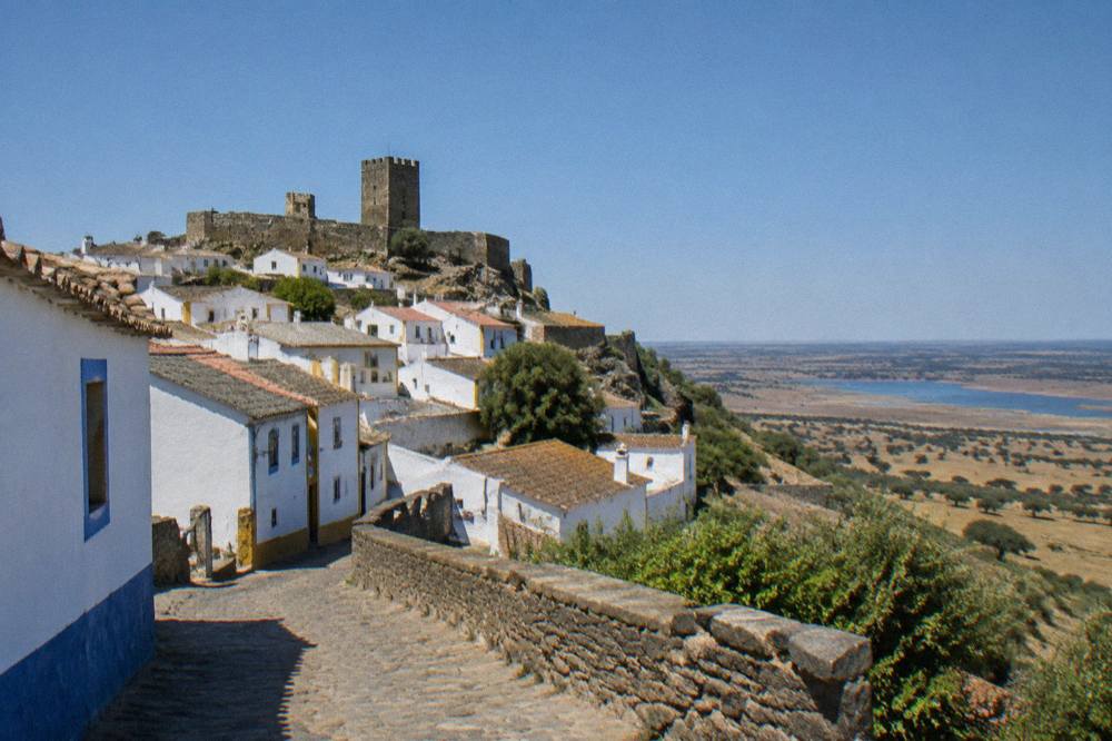 The walled village of Monsaraz seen from below, with white houses and a stone castle on a hill