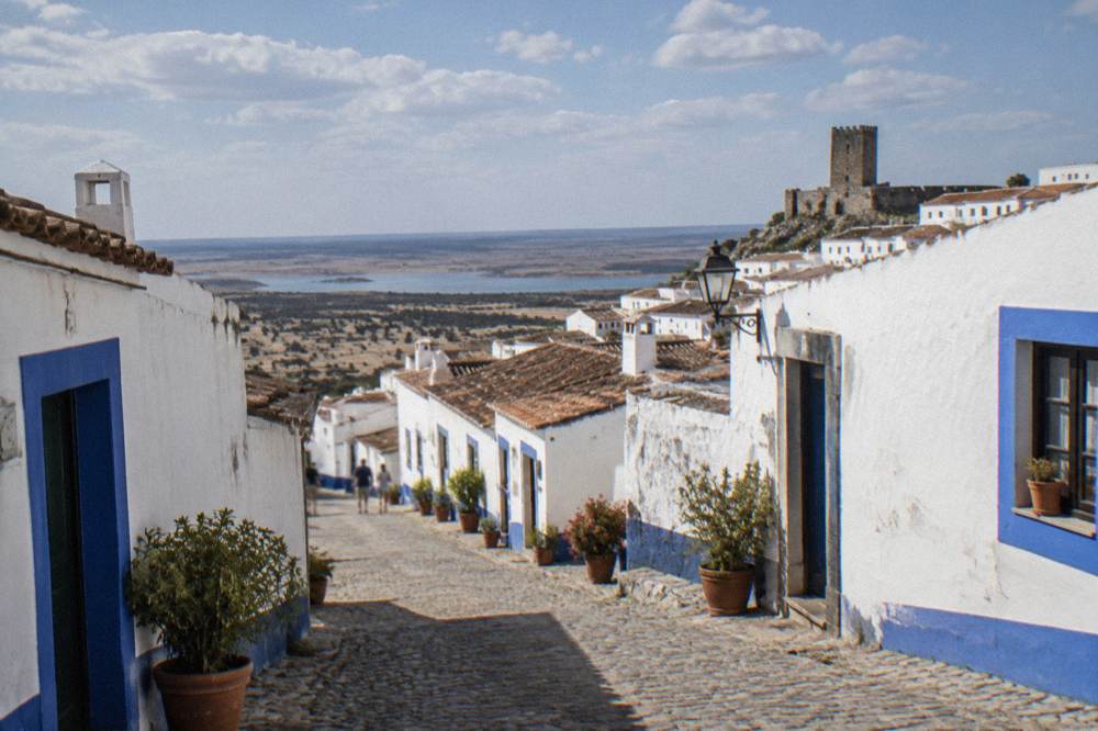 A narrow cobbled street in Monsaraz village with whitewashed houses and blue trim