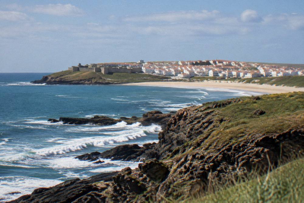 Waves breaking on dark rocks below a grassy headland on the Atlantic coast