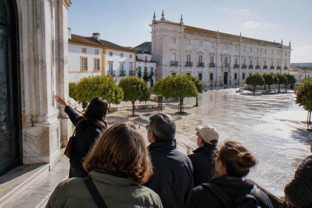 A guide showing visitors a marble doorway on a walking tour in Vila Viçosa