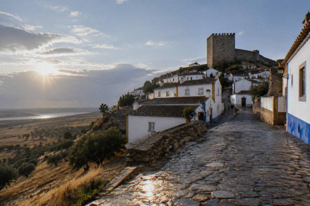 A walled village on a low hill surrounded by olive groves and dry grassland