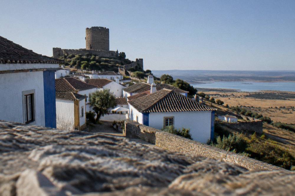 A round medieval castle keep on a hilltop above a small Portuguese village