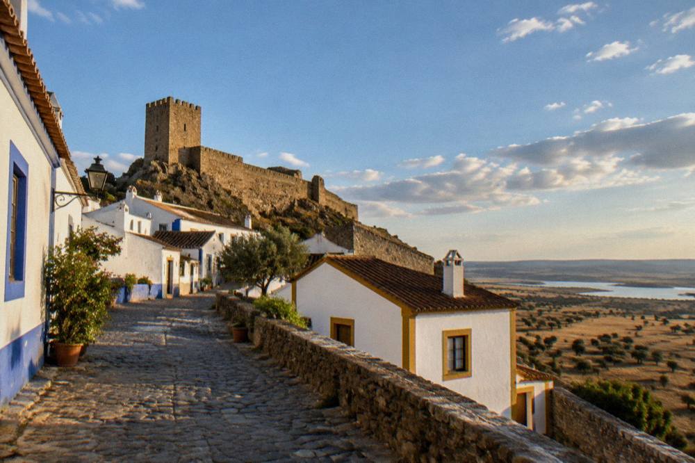 A hilltop village at golden hour with long shadows across the plain