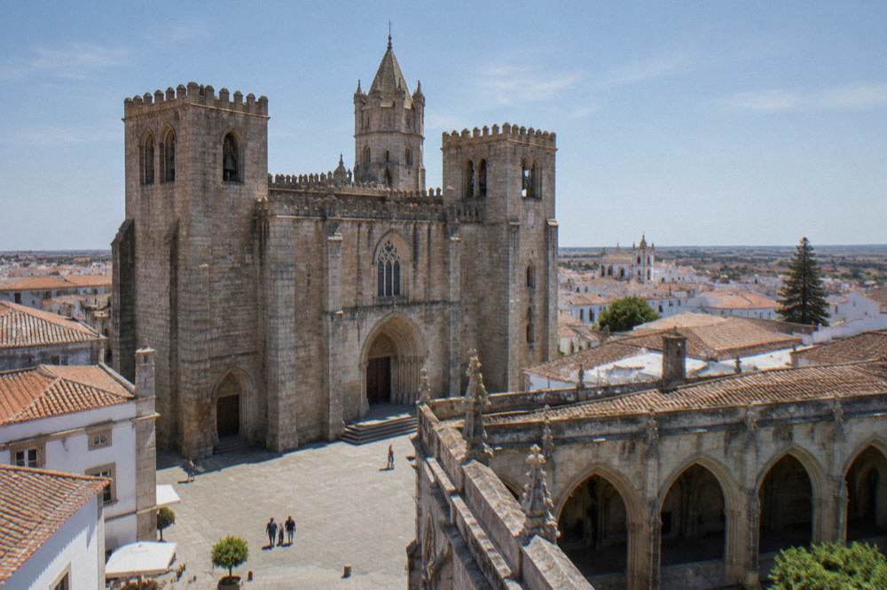 The Gothic cloister of Évora cathedral with stone arches and a view over the city rooftops from the roof terrace