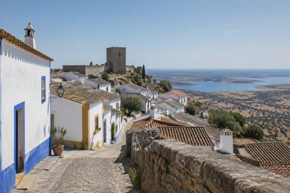 White-washed Alentejo village street with blue and yellow trim under a clear sky