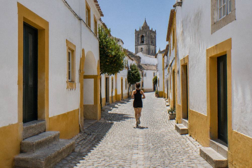Narrow whitewashed street with yellow trim inside Évora's historic centre