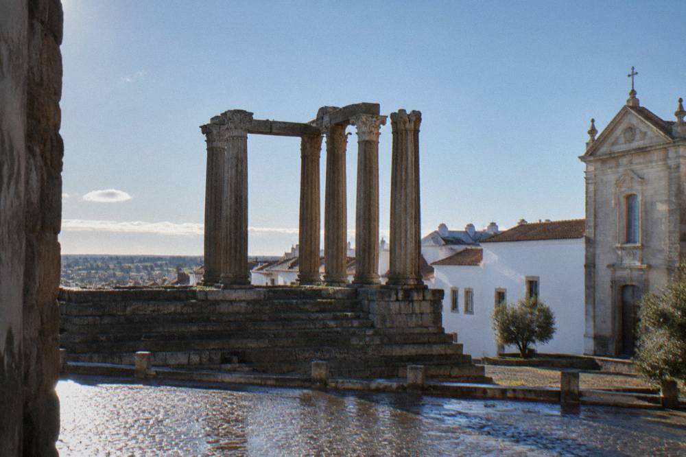 The Roman temple of Évora with stone columns rising above the historic centre rooftops