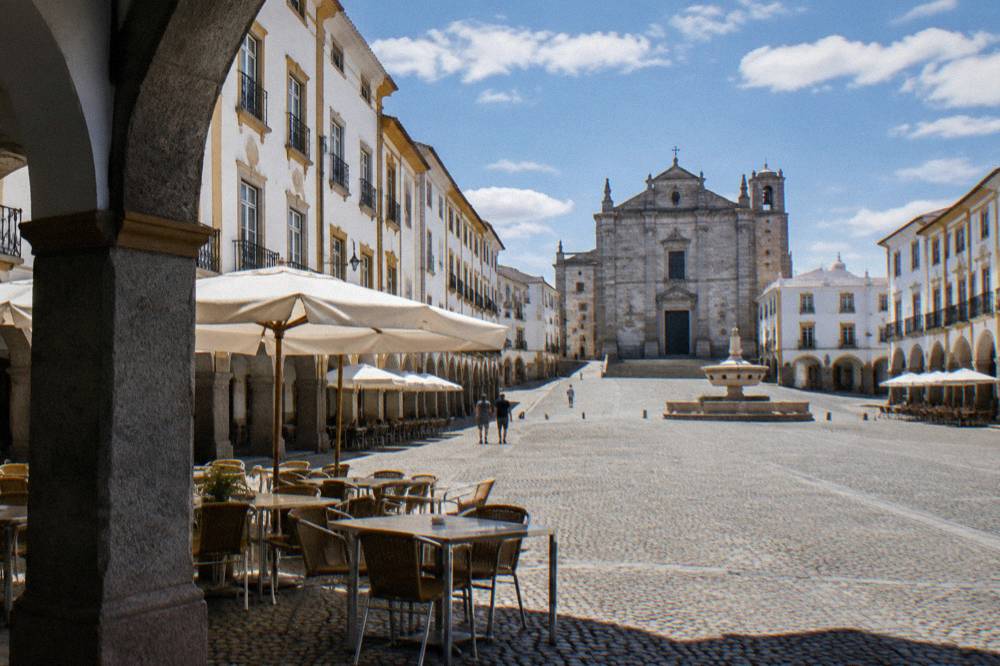 The arcaded Praça do Giraldo in Évora with café tables and the fountain at the square's end