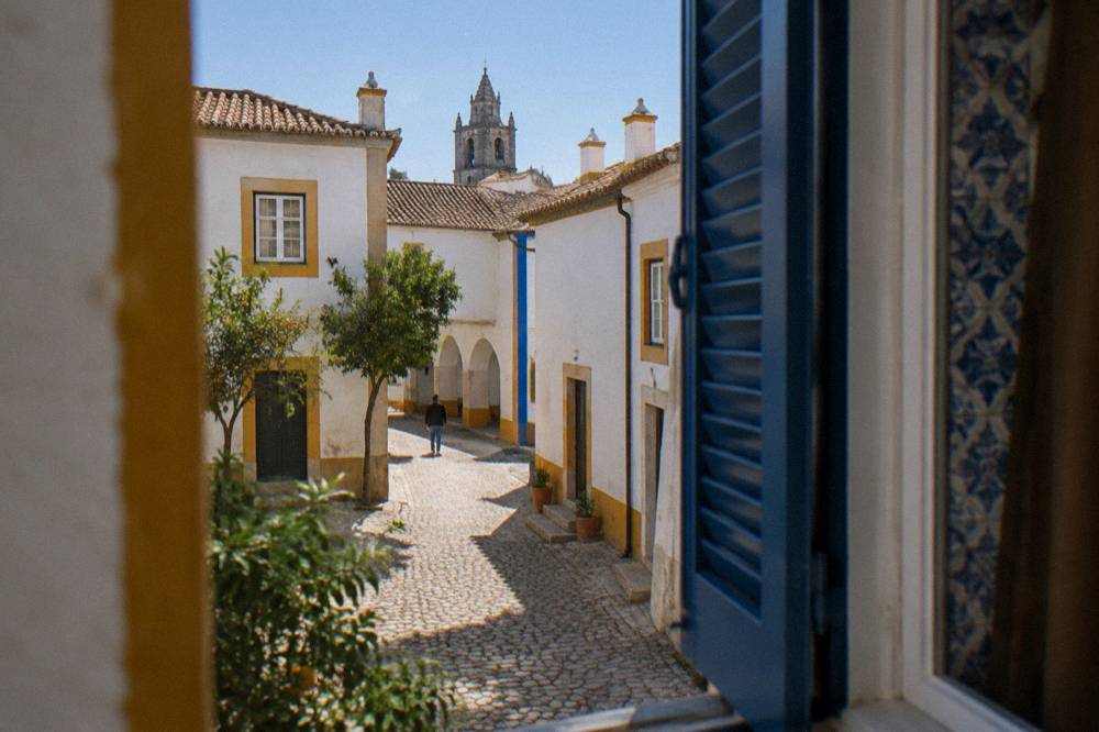 A guest room window with traditional blue tiles and shutters opening onto an Évora courtyard