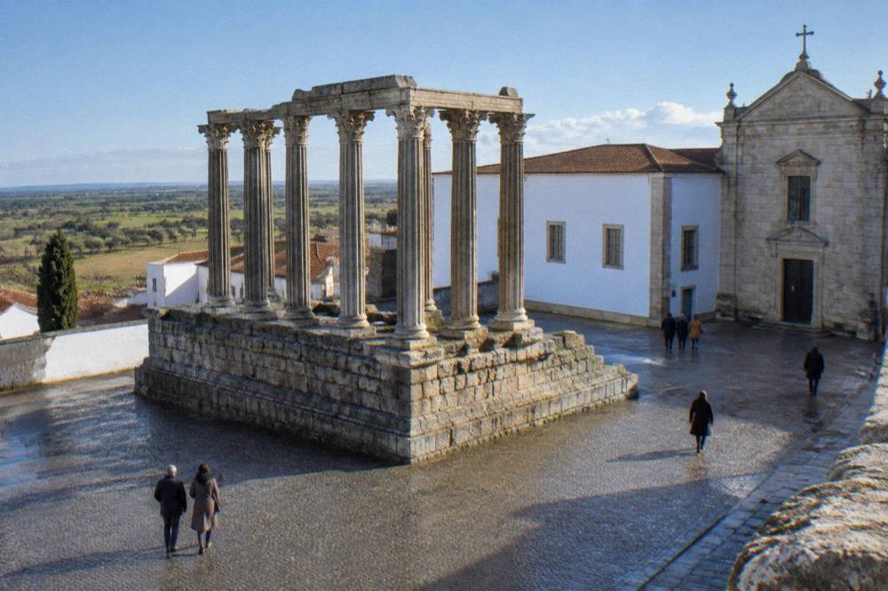 The Roman temple of Évora standing in the open square under a clear winter sky with few visitors around