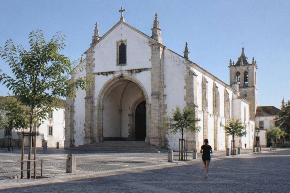 The pale stone facade of the Igreja de São Francisco in Évora under a clear sky, seen from the square outside