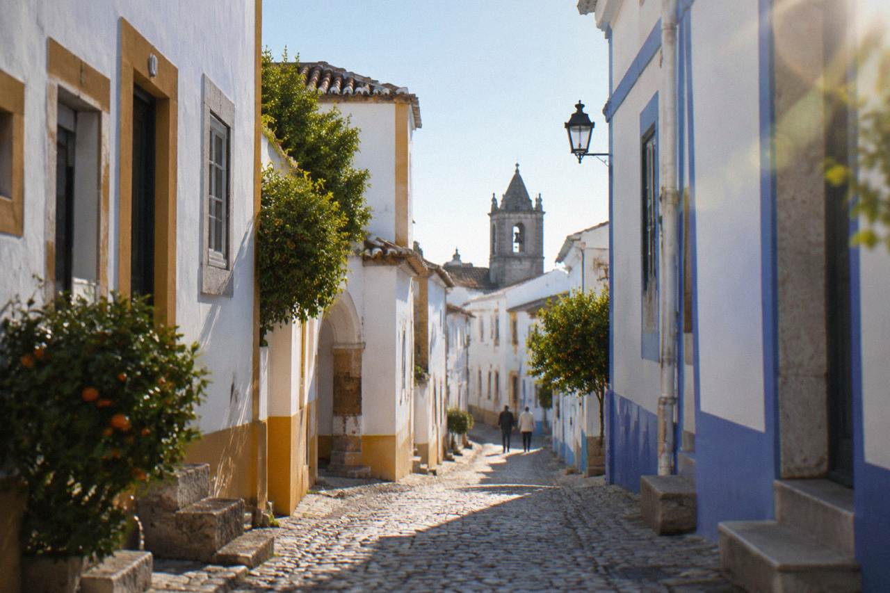 Narrow cobbled street in the historic centre of Évora with whitewashed houses and blue and yellow trim