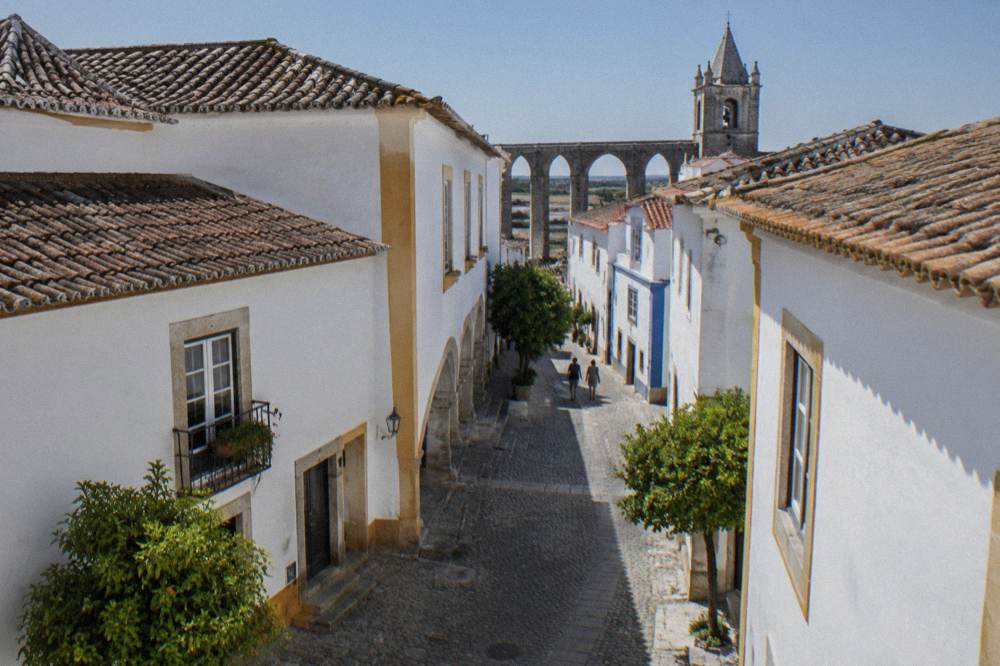 Pedestrian street inside the walls of Évora with the aqueduct arches visible between houses