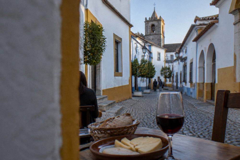 Glass of red Alentejo wine and a plate of regional cheese and bread on a tavern table