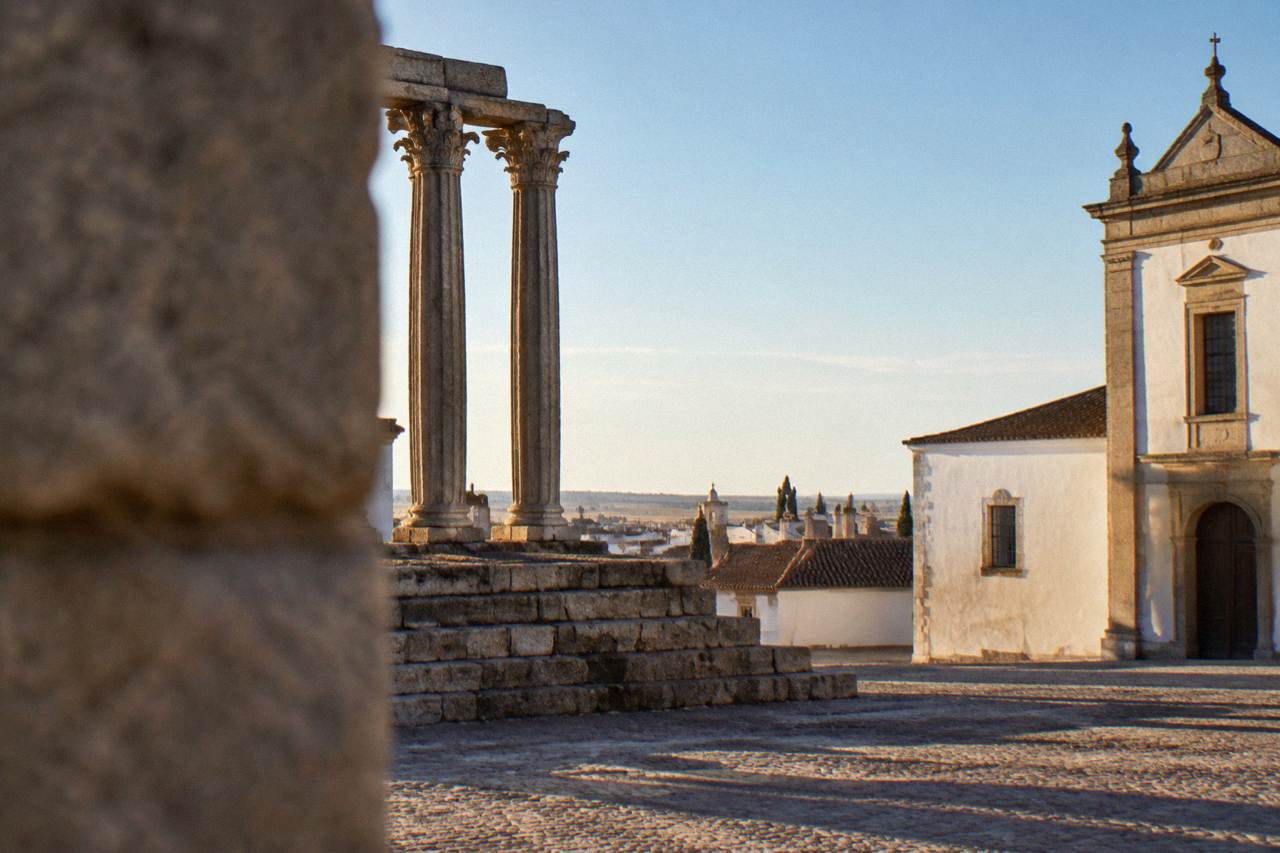 The Roman temple columns rising above the rooftops of Évora's old town at golden hour