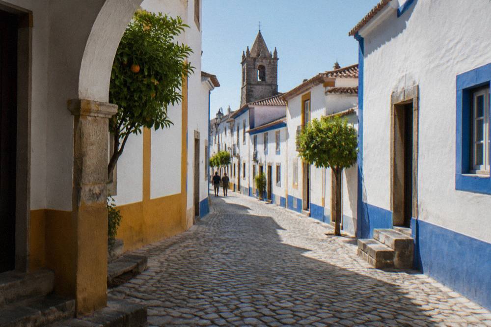 Stone-paved street in Évora's historic centre with white-washed houses and blue trim in afternoon light