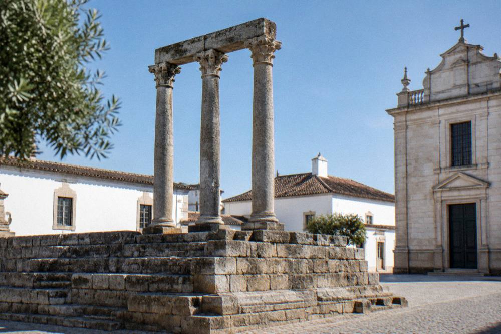 Roman temple columns in Évora seen from street level in soft morning light