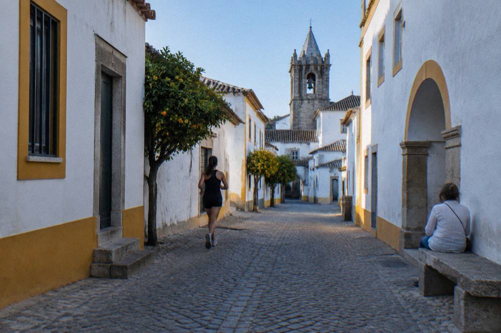 Visitor resting on a stone bench beside a whitewashed wall in an Évora square