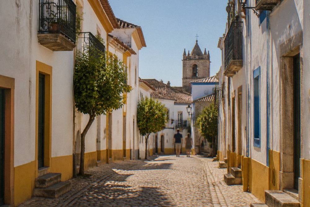 Whitewashed houses with iron balconies on a narrow street inside the walls of Évora