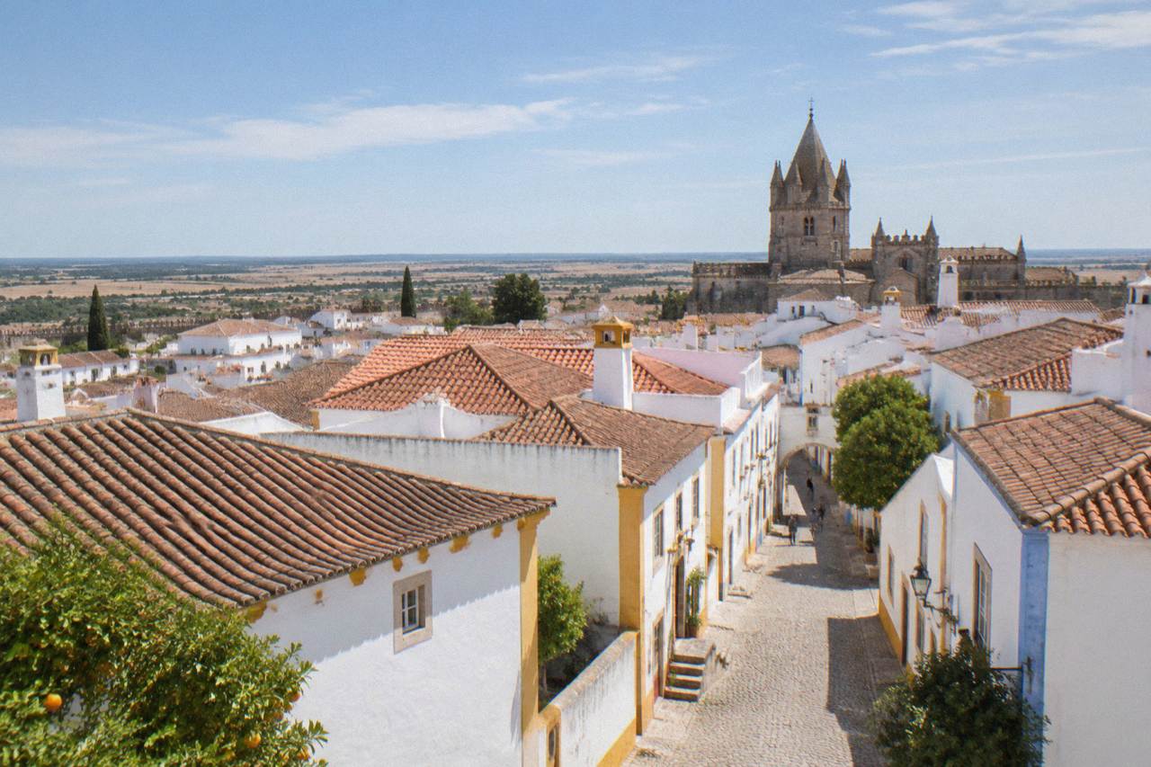 Aerial view of Évora's walled historic centre with whitewashed houses and terracotta roofs on the Alentejo plain