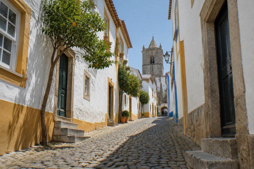 A narrow cobbled street in the historic centre of Évora with old stone walls on both sides