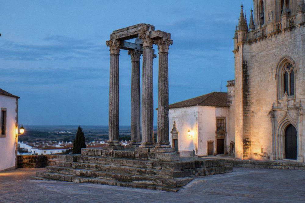 The Roman temple columns of Évora standing beside the cathedral in evening light