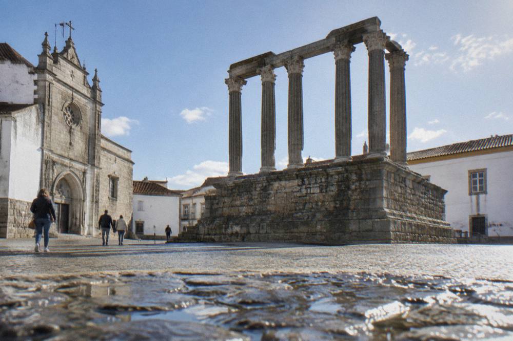 The Roman temple of Évora seen from a quiet street with pedestrians and no traffic