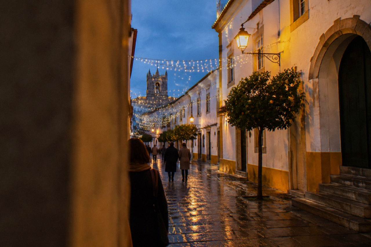 Christmas lights strung across a narrow street in the historic centre of Évora at dusk
