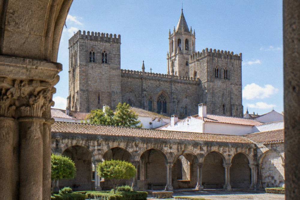 Cloister of a Portuguese cathedral with stone arches and afternoon light