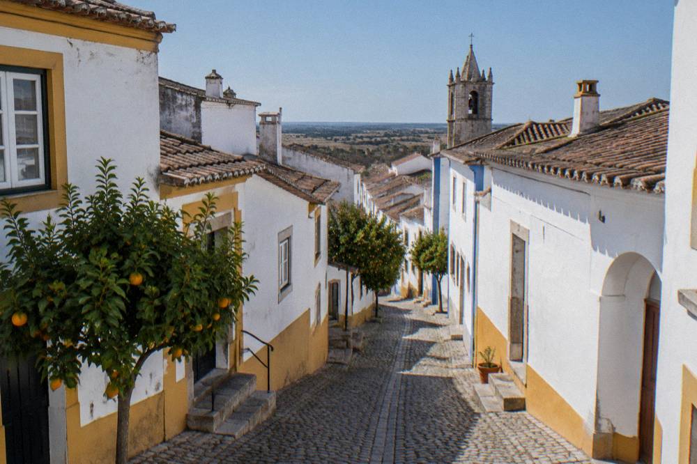 Narrow cobbled street in Évora with whitewashed walls and yellow trim